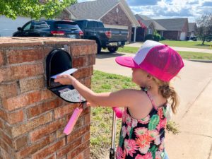 Aly's daughter putting a "Christmas in April" card in a neighbor's mailbox