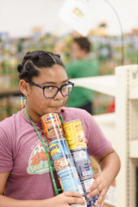 A girl holidng a stack of canned food in our places to volunteer this season article.