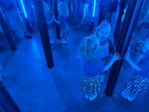 A toddler looking at herself in the mirror maze at Science Museum Oklahoma. This is a great fun idea to beat the heat.