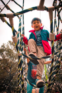 A young boy playing on a rope structure at the Yanaguana Garden Park